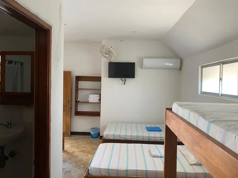 Une chambre simple avec des lits superposés et un ventilateur au plafond.
