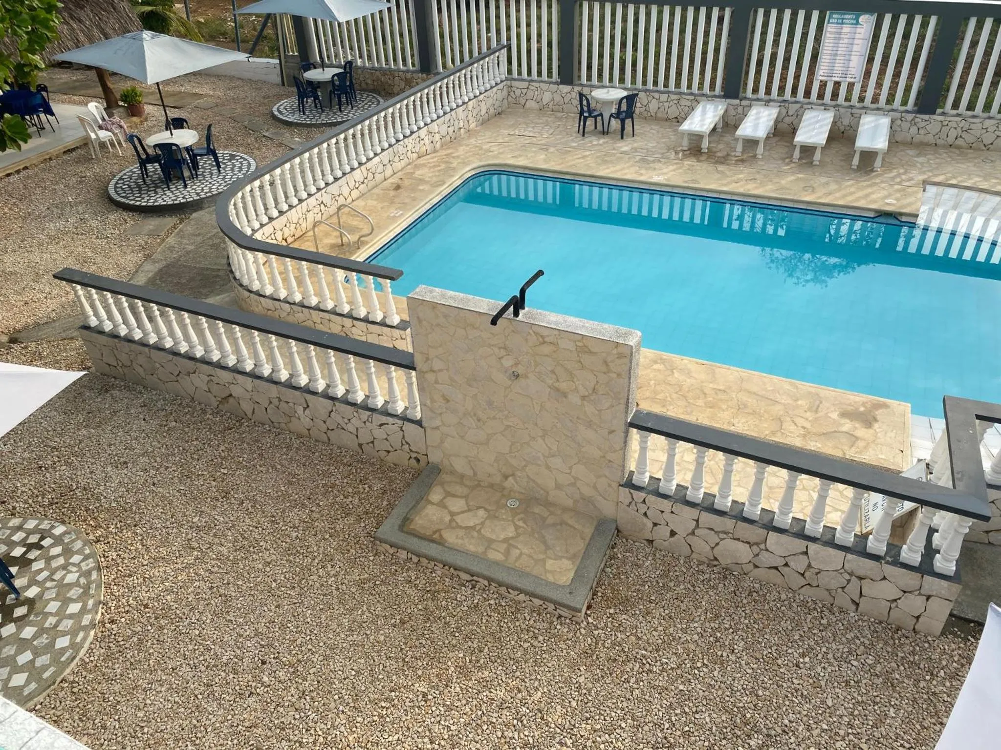 Une piscine rectangulaire entourée d'une terrasse pavée et de chaises longues.