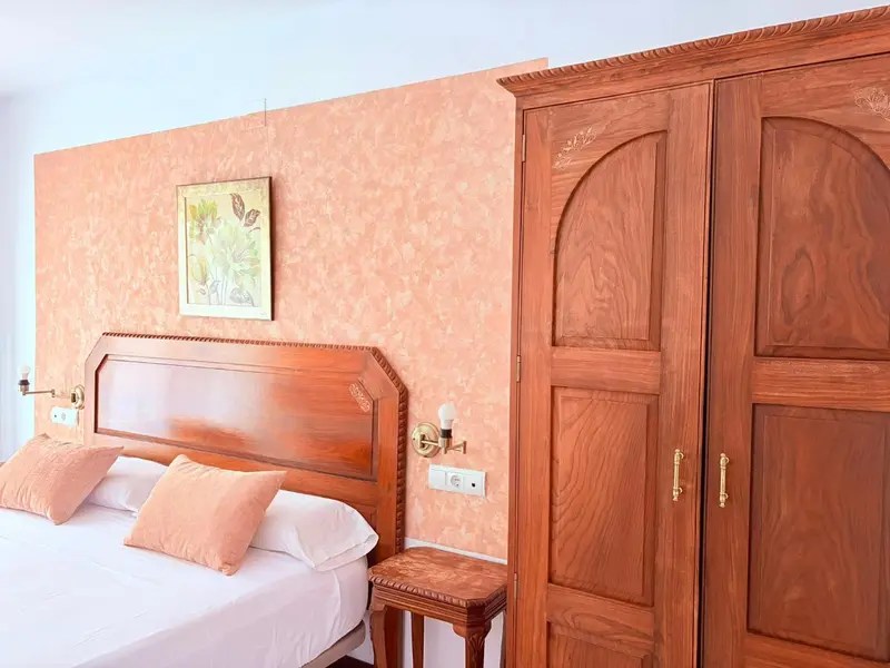 Une chambre avec un grand lit et une armoire en bois.