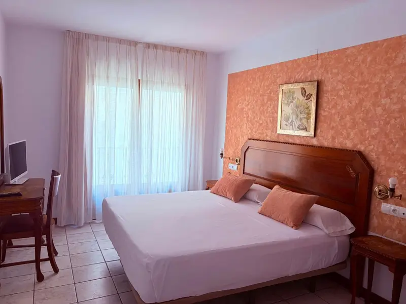 Une chambre lumineuse avec un grand lit et un bureau.