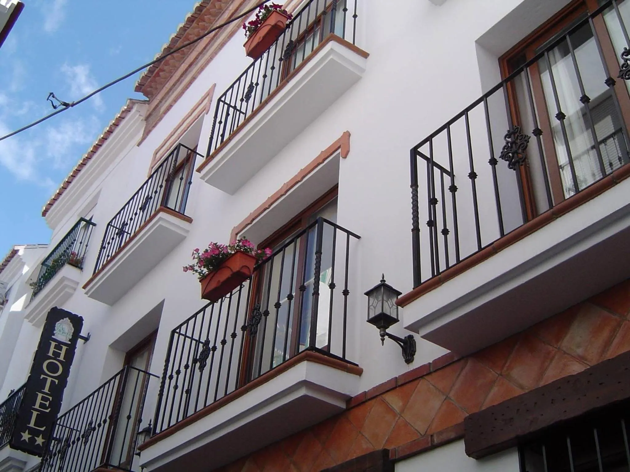 Facade d'un bâtiment blanc avec des balcons en fer forgé ornés de fleurs.