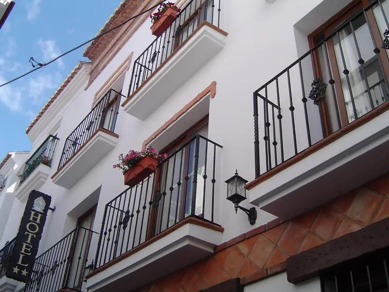 Facade d'un bâtiment blanc avec des balcons en fer forgé ornés de fleurs.