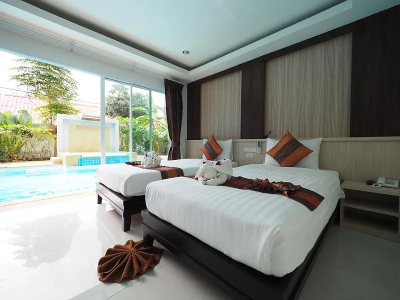 Deux lits jumeaux préparés dans une chambre lumineuse avec vue sur une piscine.