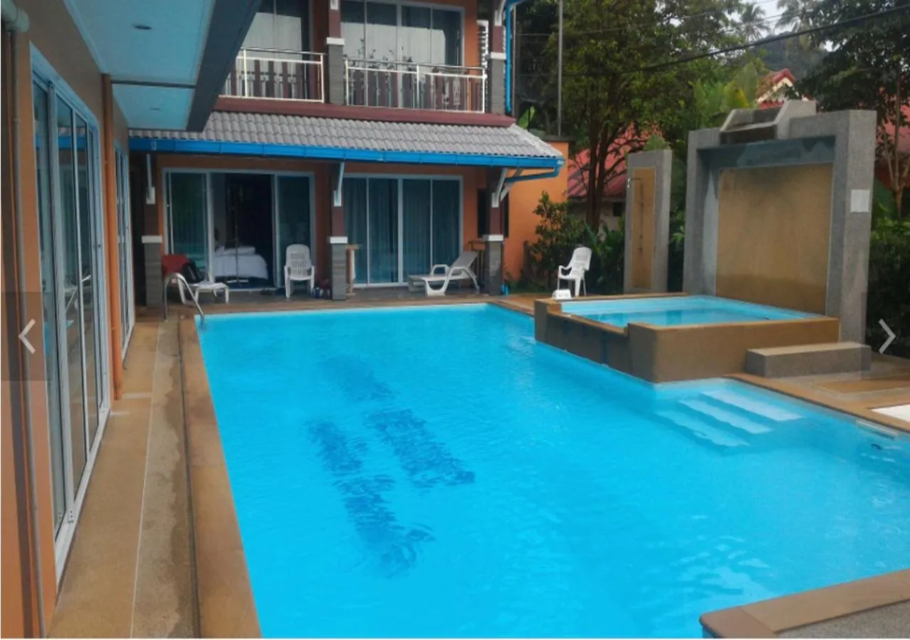 Une piscine bleue est entourée d'une terrasse avec des chaises longues et un bâtiment à l'arrière-plan.