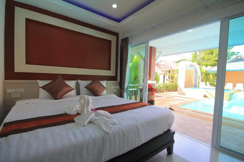 Une chambre lumineuse avec un grand lit et vue sur une piscine.