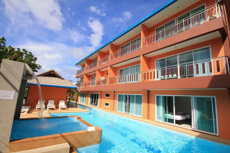 Bâtiment orange à plusieurs étages avec des balcons et une piscine au premier plan.