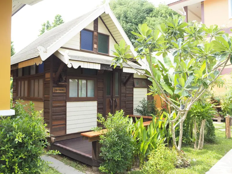 Petite maison en bois avec un toit pointu et une terrasse.