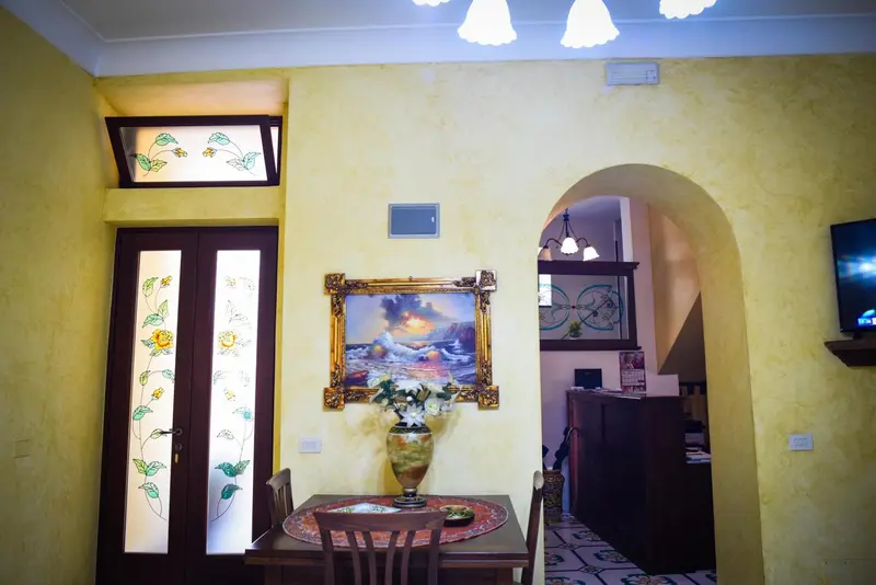Une table ronde avec deux chaises est placée devant un tableau dans un intérieur lumineux.