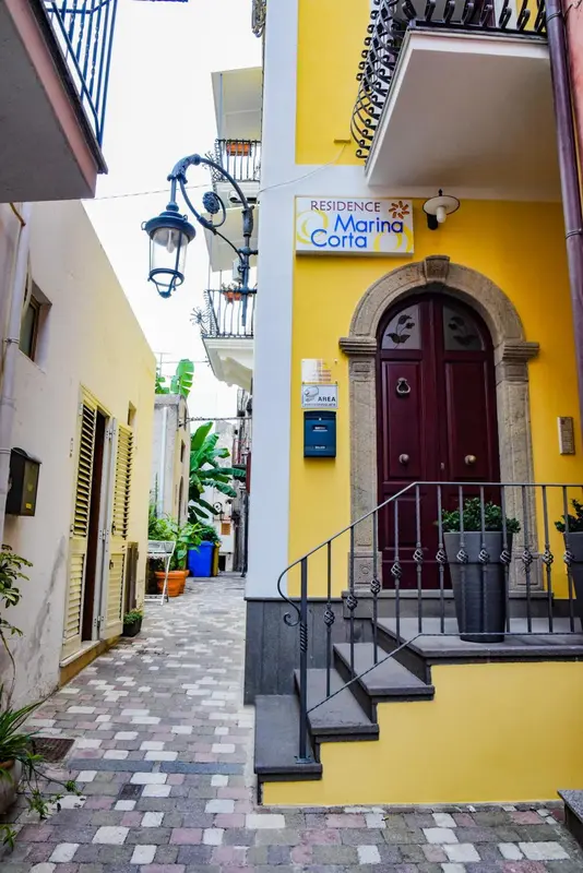 Façade jaune d'un immeuble avec une entrée et un escalier.