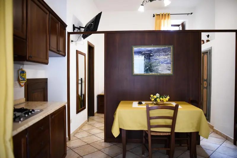 Une cuisine ouverte sur une salle à manger avec une table jaune et des chaises en bois.