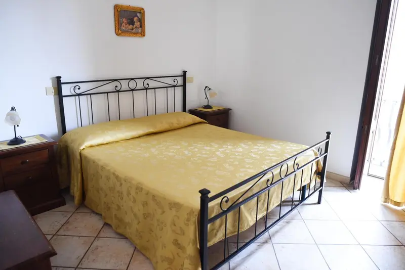 Une chambre lumineuse avec un lit recouvert d'une couverture jaune.
