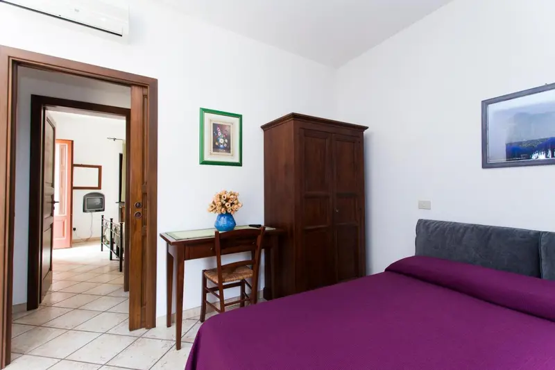 Une chambre lumineuse avec un lit violet et un bureau en bois.