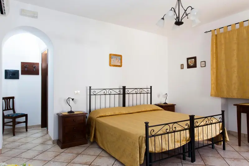Une chambre lumineuse avec un lit recouvert d'une couverture jaune et un mobilier en bois sombre.