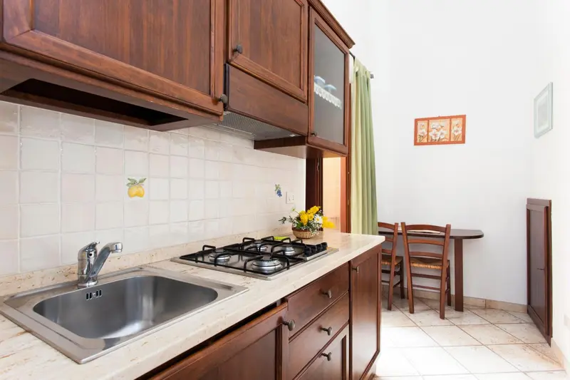 Une cuisine avec un évier en inox et une plaque de cuisson à gaz.