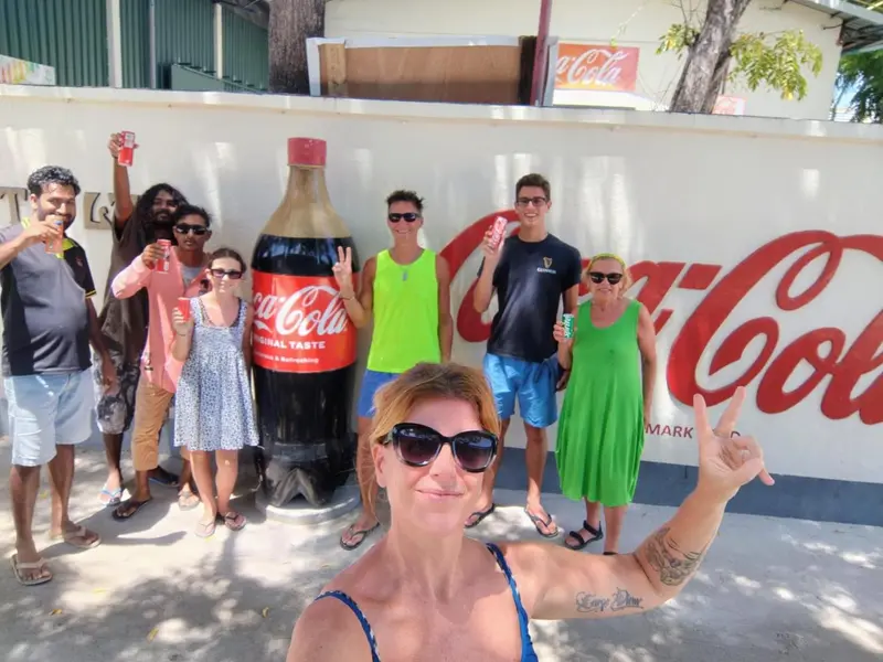 Groupe de personnes souriantes posant devant un mur décoré avec des logos Coca-Cola.