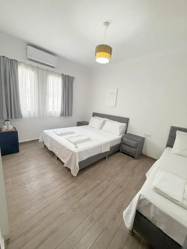 Chambre lumineuse avec un lit double et un lit simple.