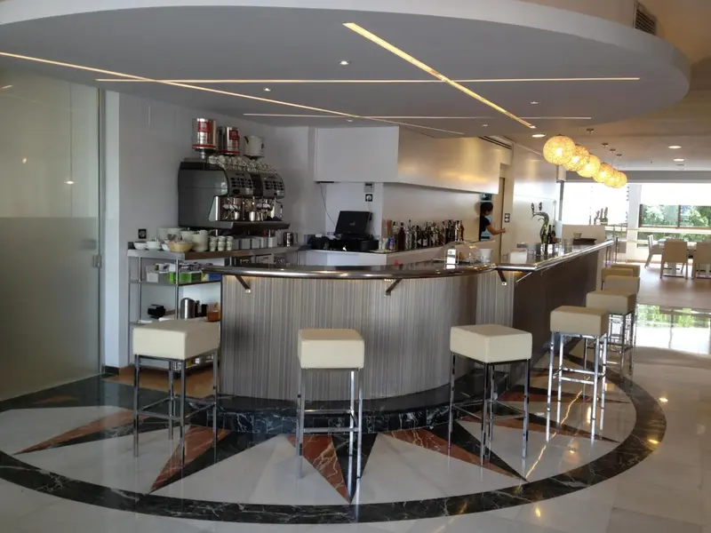 Un comptoir de bar incurvé avec des tabourets et des bouteilles.