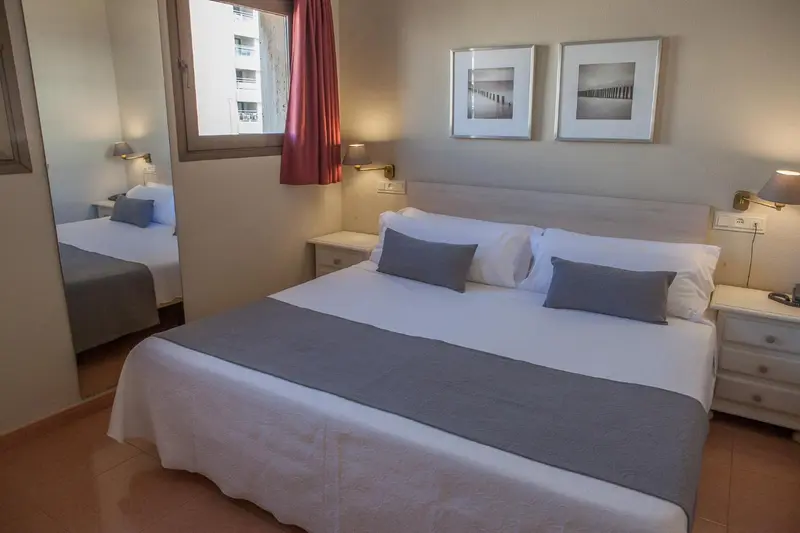 Une chambre lumineuse avec deux lits simples et des oreillers gris.