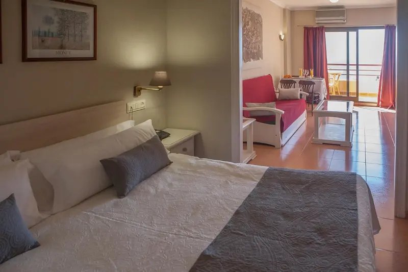 Une chambre à coucher lumineuse s'ouvre sur un espace de vie avec canapé et table.