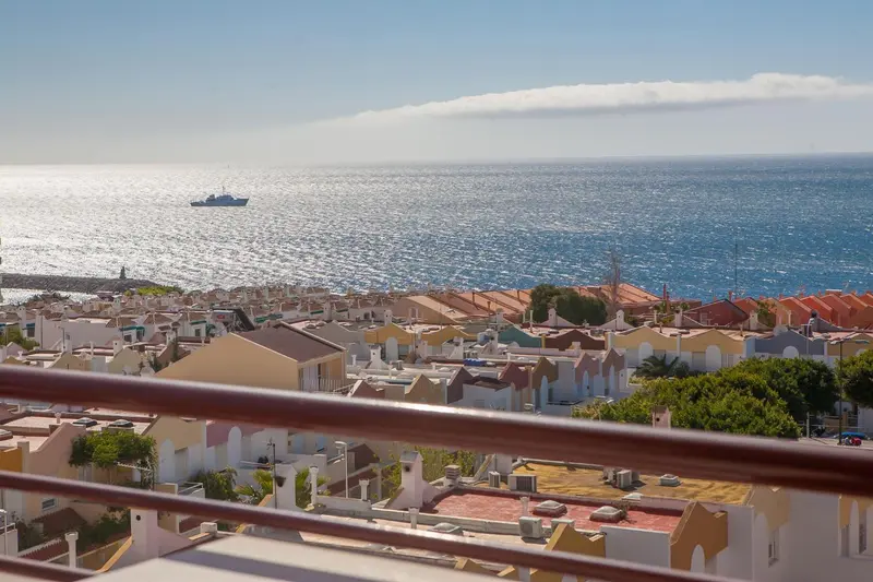 Vue d'ensemble sur un littoral avec des bâtiments et la mer scintillante.