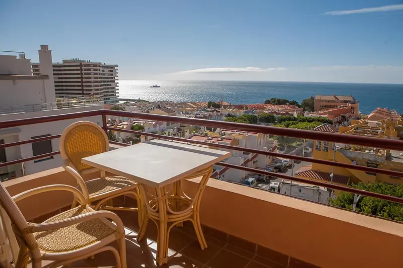 Terrasse avec mobilier en osier donnant sur une vue urbaine et maritime.