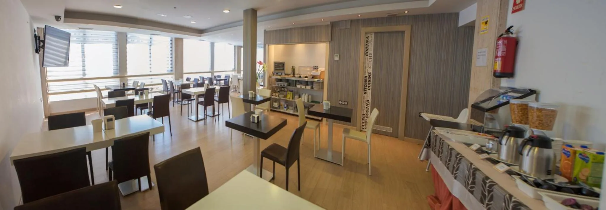 Une salle lumineuse avec des tables et des chaises, un comptoir de buffet et des étagères remplies de produits.