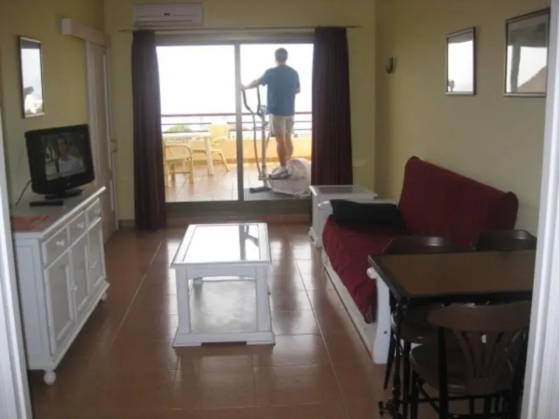 Interieur lumineux avec canape rouge et vue sur une terrasse.