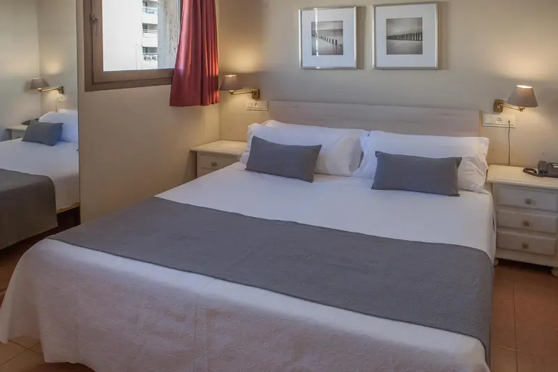 Une chambre lumineuse avec deux lits simples et des tables de chevet.