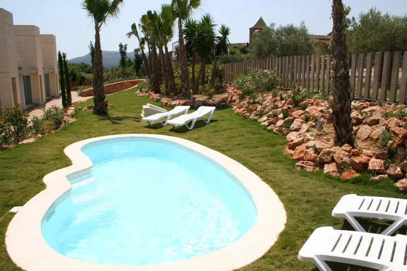 Petite piscine et transats sur une pelouse verdoyante.