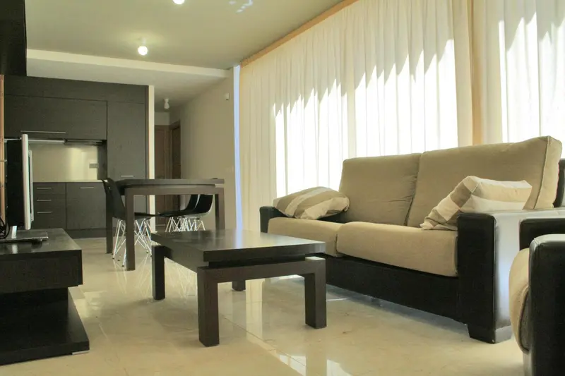 Un salon moderne avec un canapé beige et une table basse en bois sombre.