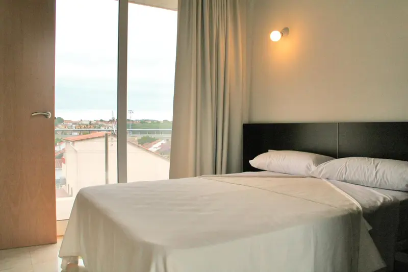 Une chambre lumineuse avec un grand lit et une vue sur la ville.