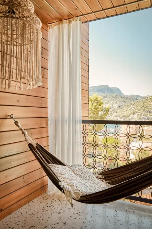 Un hamac suspendu sur une terrasse en bois avec vue sur un paysage montagneux.