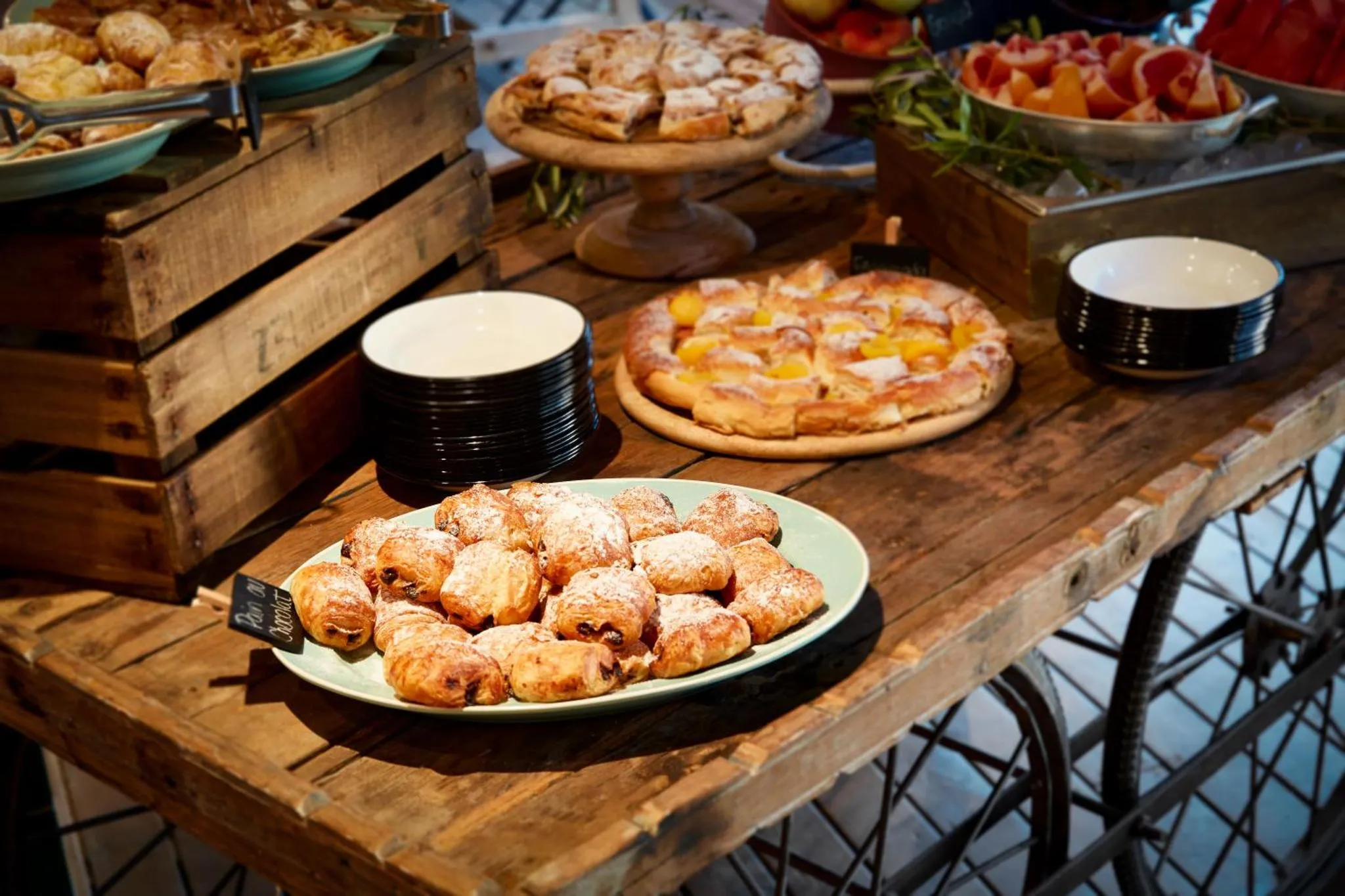 Présentation de pâtisseries et de fruits frais sur un buffet en bois.