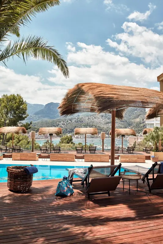 Terrasse avec transats et parasols en bord de piscine, vue sur la mer.