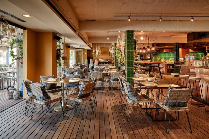 Une salle à manger lumineuse avec des tables et des chaises en osier.
