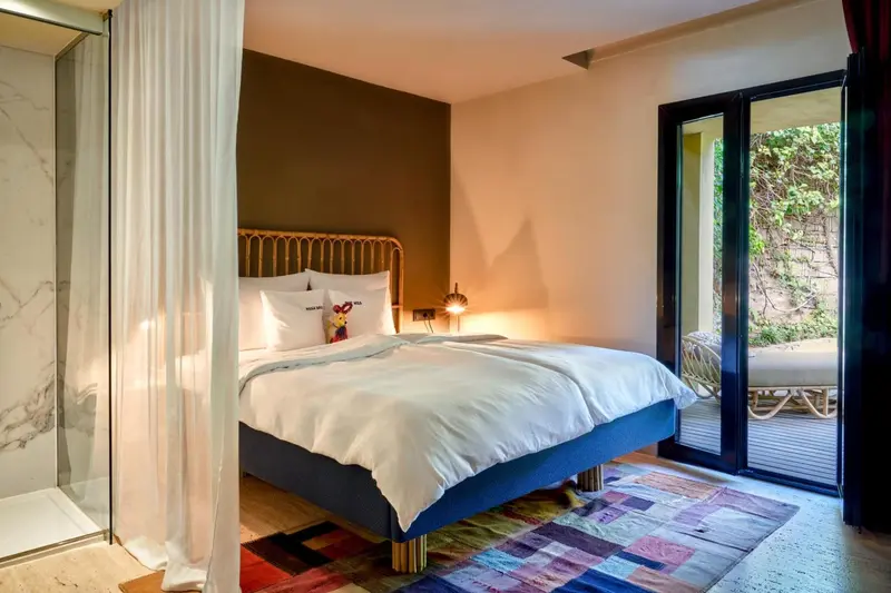 Une chambre lumineuse avec un grand lit et un accès à une terrasse.