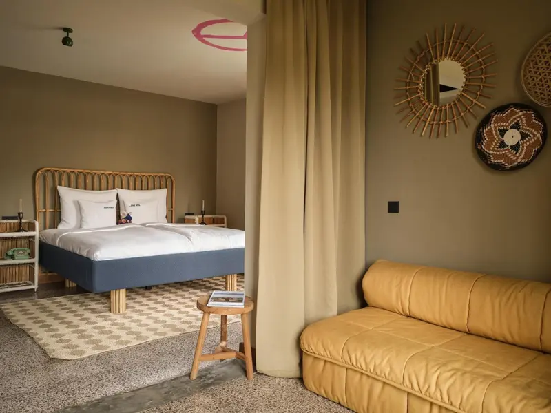 Une chambre lumineuse avec un lit et un coin salon.