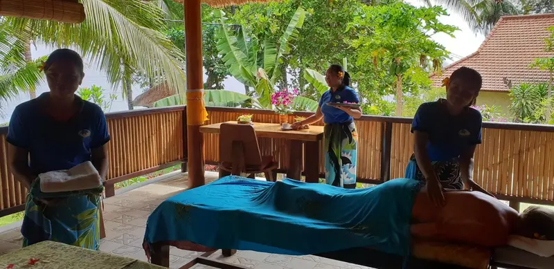 Des personnes offrent des massages sur une terrasse en bois.