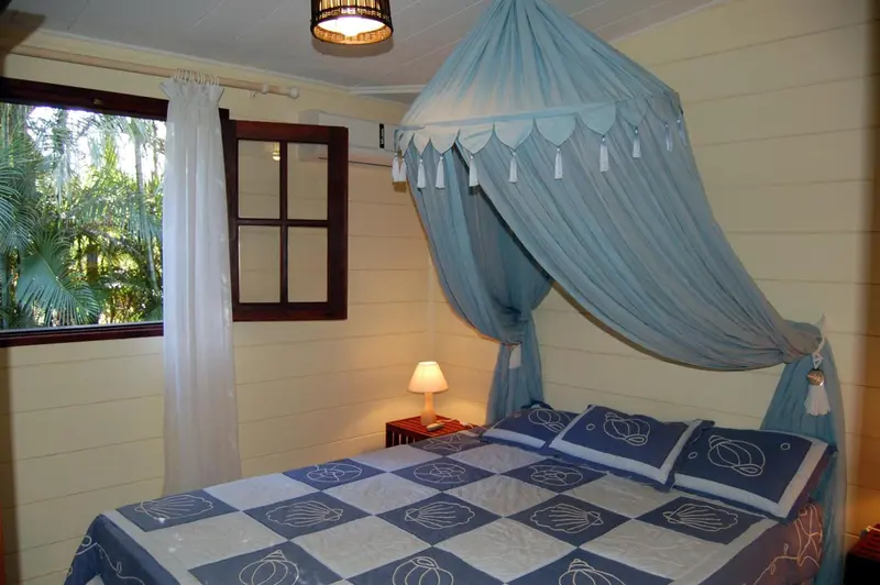 Une chambre lumineuse avec un lit à baldaquin et une vue sur la végétation.