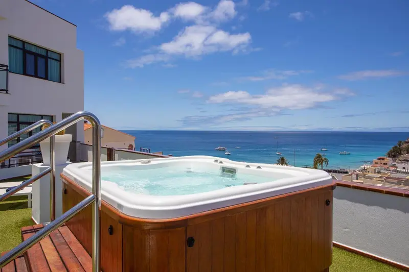 Un jacuzzi sur une terrasse avec vue sur la mer et le ciel bleu.