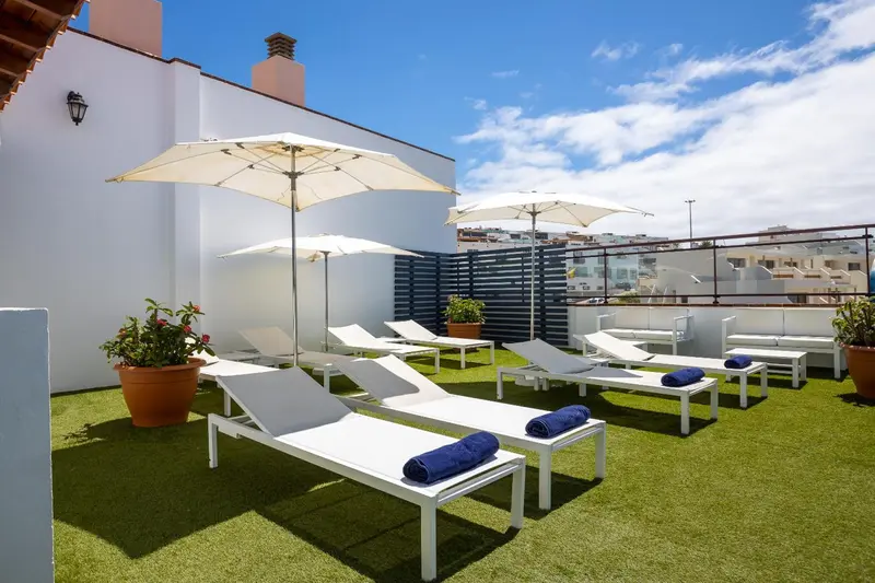Terrasse avec transats et parasols sur gazon synthétique.