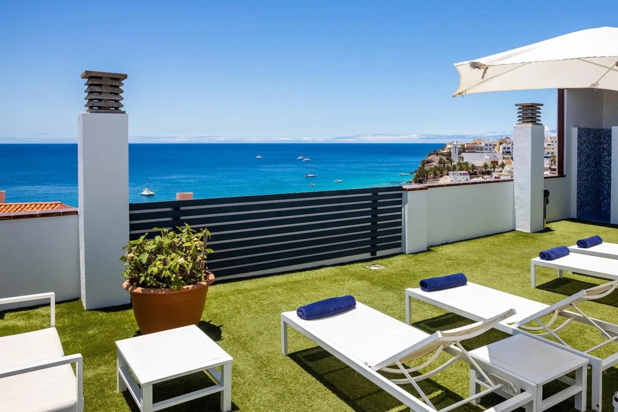 Transats blancs disposés sur une terrasse avec vue sur la mer.