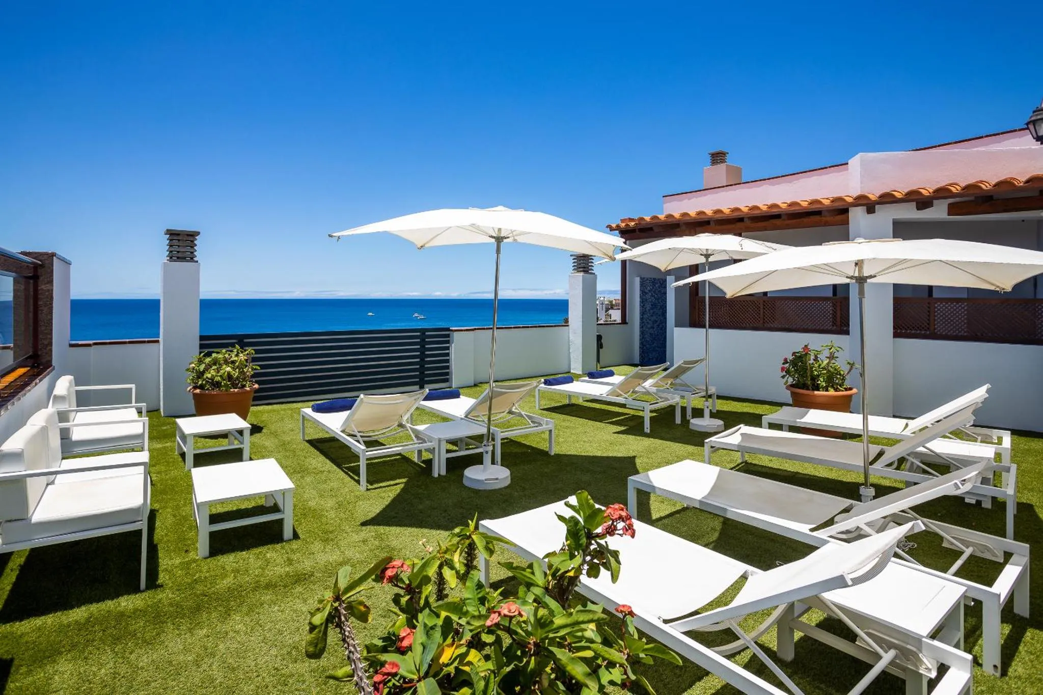 Terrasse aménagée avec transats et parasols, vue sur la mer.