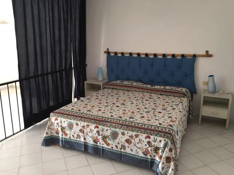 Une chambre lumineuse avec un grand lit recouvert d'une courtepointe fleurie.
