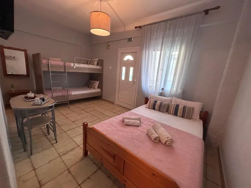 Une chambre avec un lit superposé et un lit double, une table et des chaises.
