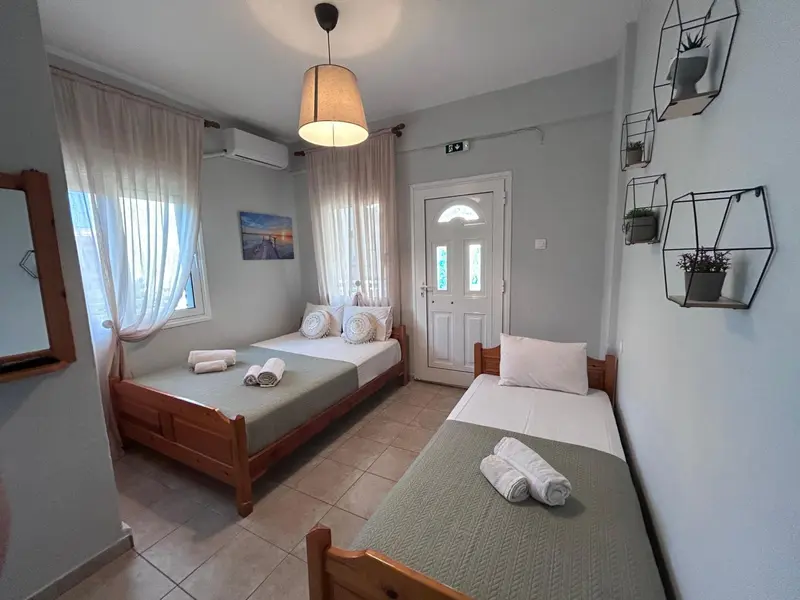 Une chambre lumineuse avec deux lits simples et un lit individuel.