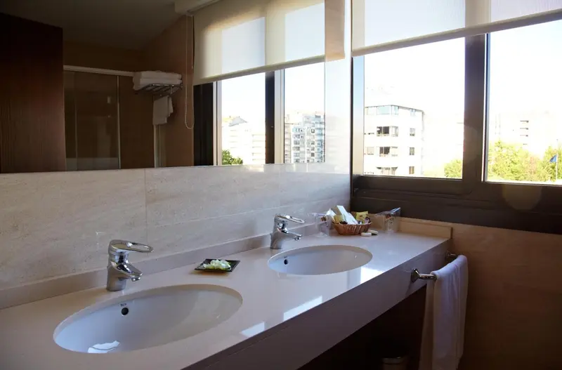 Une salle de bain lumineuse avec deux vasques et un grand miroir.