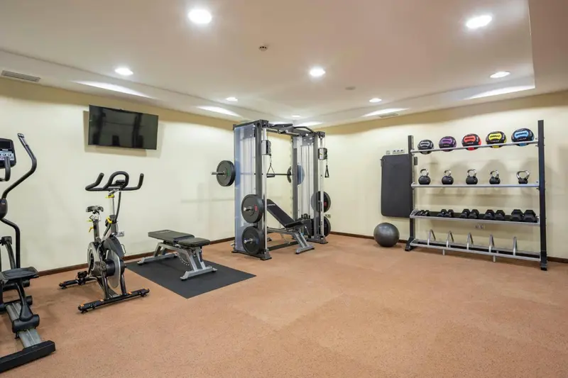 Une salle de sport lumineuse avec des équipements de musculation et de cardio.