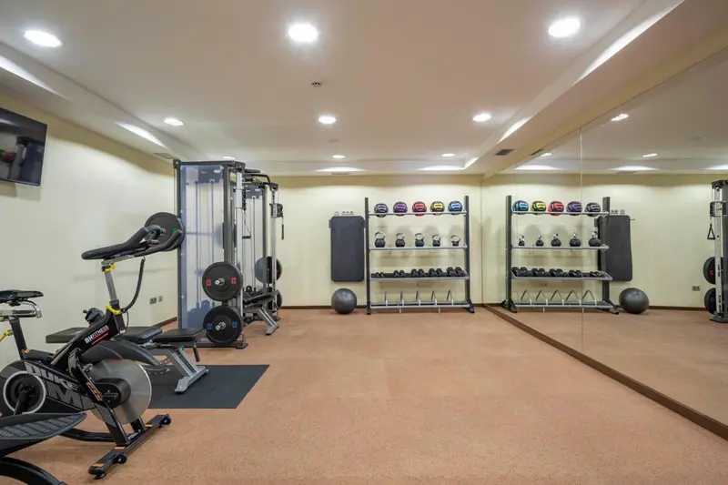 Une salle de sport lumineuse avec des équipements de musculation et des miroirs.