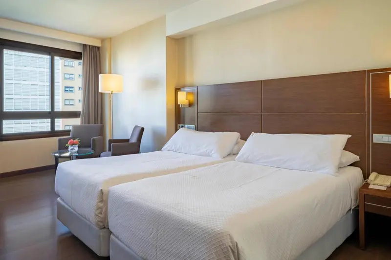 Une chambre lumineuse avec un grand lit et un fauteuil.